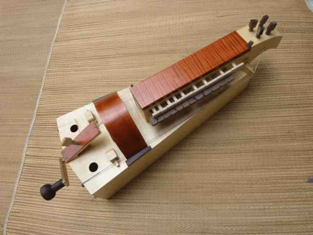 Ghironda Nova in legno chiaro, vista dall’alto su stuoia